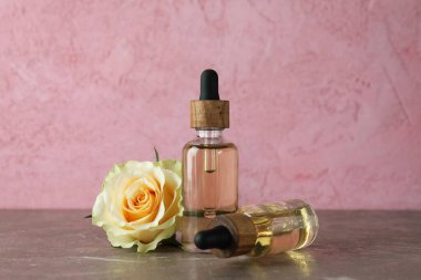 Gül esanslı şişeler ve pembe arka planda gül