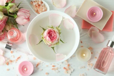 Beyaz ahşap masa üzerinde gül yağı içeren cilt bakımı kavramı