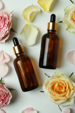 Beyaz arka planda gül yağı içeren cilt bakımı kavramı