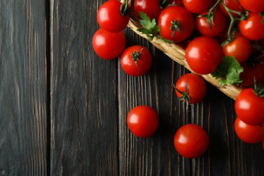 Tahta arka planda vişneli domates sepeti.