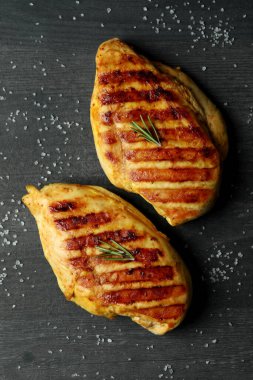 Koyu ahşap arka planda ızgara tavuk eti ve tuz.