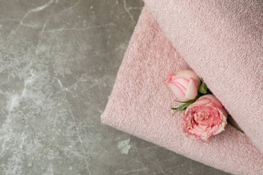 Gri desenli masada pembe katlanmış havlular ve güller.