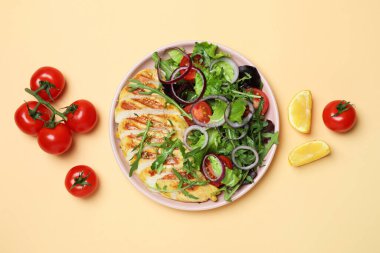 Kızarmış tavuklu salata ve bej arka planda malzemeler.