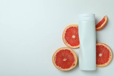 Beyaz arka planda duş jeli ve greyfurt dilimleri