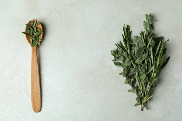 Wooden spoon with herbs on white textured background