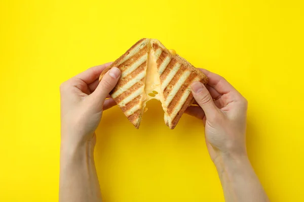 Mãos Femininas Segurar Sanduíche Grelhado Com Queijo Fundo Amarelo — Fotografia de Stock