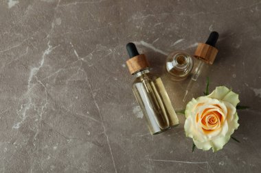 Gri desenli arka planda gül yağı içeren şişeler