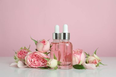 Pembe arka planda gül yağı içeren cilt bakımı kavramı