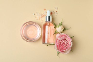 Bej arka planda gül yağı içeren cilt bakımı kavramı, üst görünüm