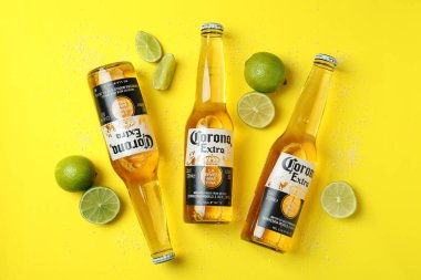 Bir şişe Corona Extra, sarı arka planda limon ve tuz.