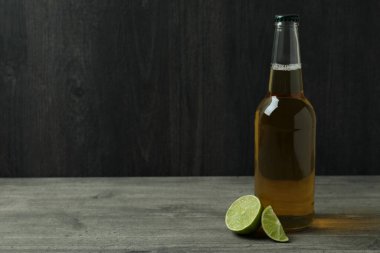 Bir şişe bira ve limon, koyu ahşap arka plana karşı.