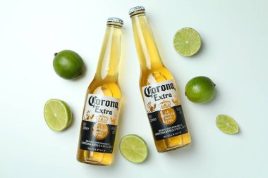 Bir şişe Corona Extra ve beyaz arka planda limonlar