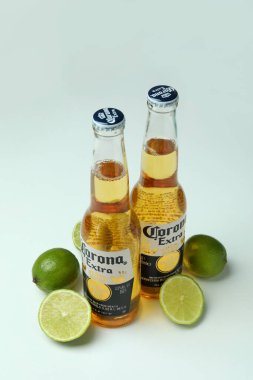 Bir şişe Corona Extra ve beyaz arka planda limonlar