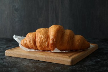 Koyu arkaplanda kruvasan olan tahta, kapat