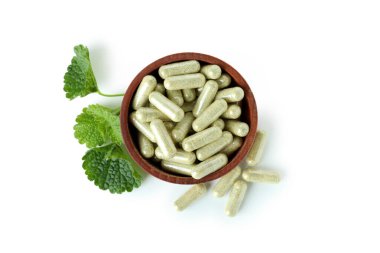 Beyaz arka planda izole bitkisel toz kapsülleri ile kase