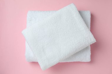 Pembe arka planda katlanmış temiz havlular, üst manzara