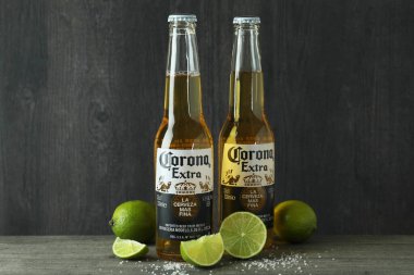 Bir şişe Corona Extra ve koyu ahşap arka plana karşı limon.