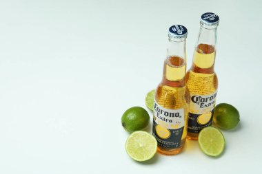 Bir şişe Corona Extra ve beyaz arka planda limonlar