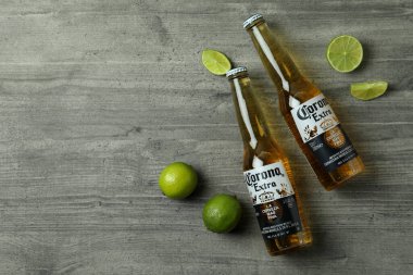 Bir şişe Corona Extra ve gri desenli arka planda limon.