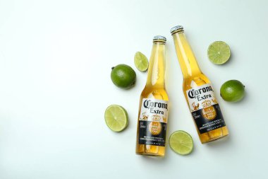 Bir şişe Corona Extra ve beyaz arka planda limonlar