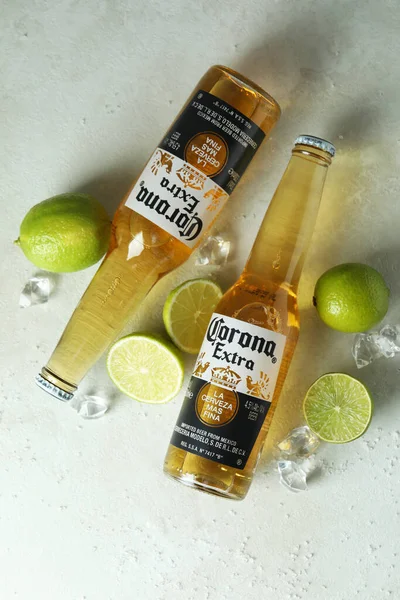 Corona Extra, limes, salt and ice on white textured background