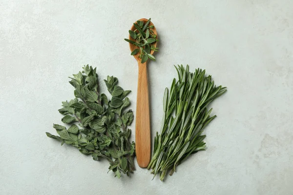 Wooden spoon with herbs on white textured background