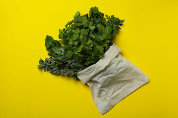 Bag with different herbs on yellow background, top view