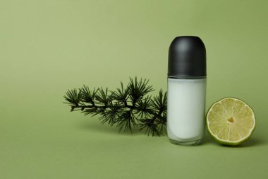Yeşil arka planda boş deodorant, ladin dalı ve limon.