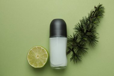 Yeşil arka planda boş deodorant, ladin dalı ve limon.