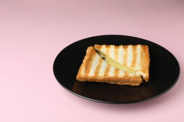 Pembe arka planda lezzetli ızgara sandviç tabağı.