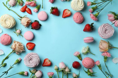 Mavi arka planda makarna, marşmelov, çiçek ve çilek.