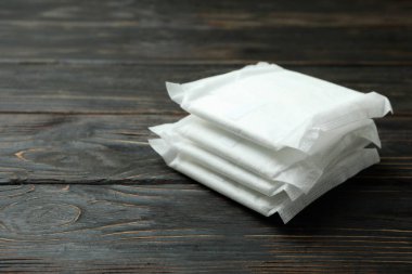 Ahşap arka planda bir yığın hijyenik ped.