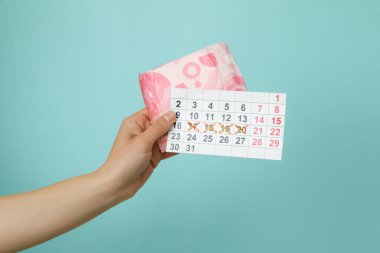 Mavi arka planda kadın el ele tutuşma takvimi ve hijyen pedi