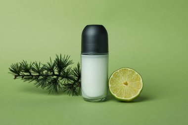 Yeşil arka planda boş deodorant, ladin dalı ve limon.