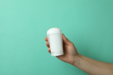 Kadın eli arkaplanda boş bir deodorant tutuyor