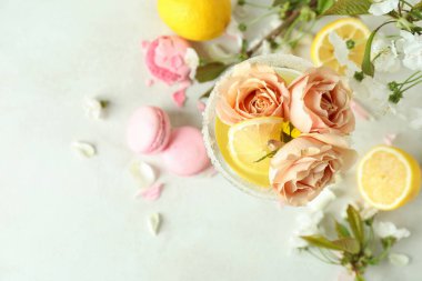 Beyaz desenli masa üzerinde bir bardak kokteyl, malzeme ve çiçek.