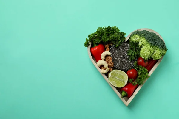 Healthy food in heart on mint background, space for text