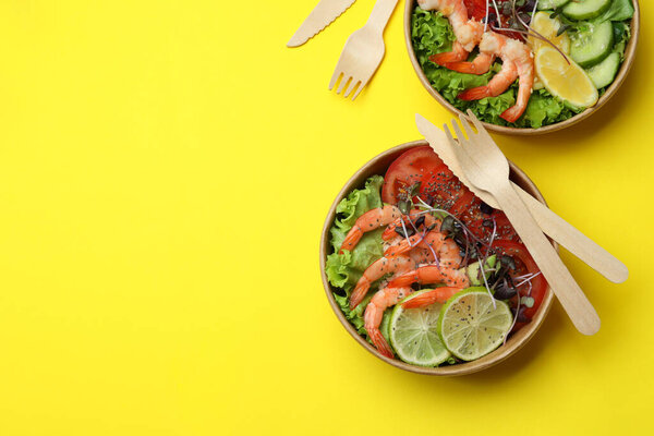Concept of tasty eating with shrimp salads on yellow background