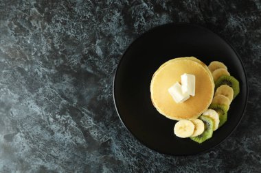 Tereyağlı gözleme tabağı, kivi ve muz siyah dumanlı masada.