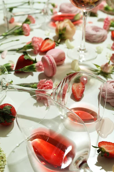 Wine, sweet food and flowers on white table