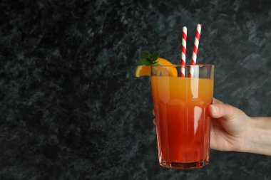 Kadın eli siyah dumanlı arka planda tekila kokteyli tutuyor.