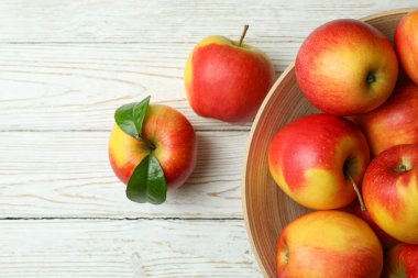 Beyaz ahşap masada kırmızı elmalı kase