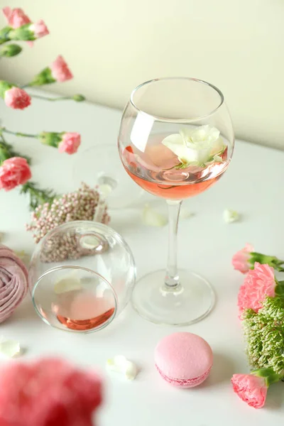 Wine, sweet food and flowers on white table