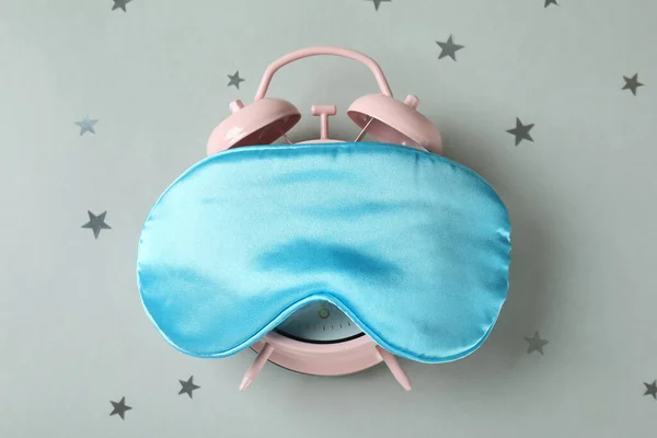 目覚まし時計グレーの背景に睡眠マスク — ストック写真