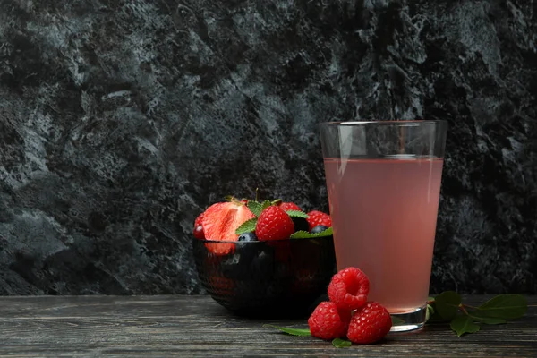 Bowl with berry mix and juice on wooden table