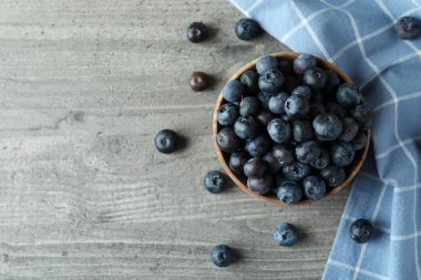 Gri desenli arka planda bir kase taze yaban mersini.