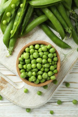 Bezelye tohumlu kase ve ahşap zemin üzerinde taze bezelye.