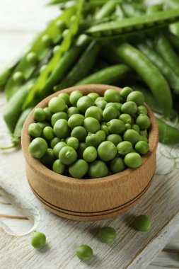 Bezelye tohumlu kase ve ahşap zemin üzerinde taze bezelye.