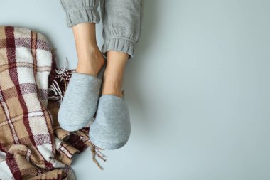 Gri arka planda gri terlikler giyen kadın bacakları.