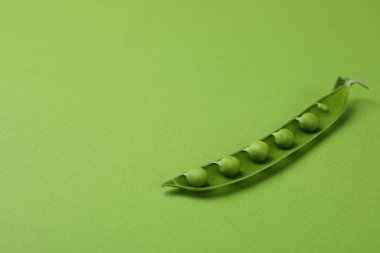 Yeşil arka planda tohumları olan yeşil bezelye kabuğu